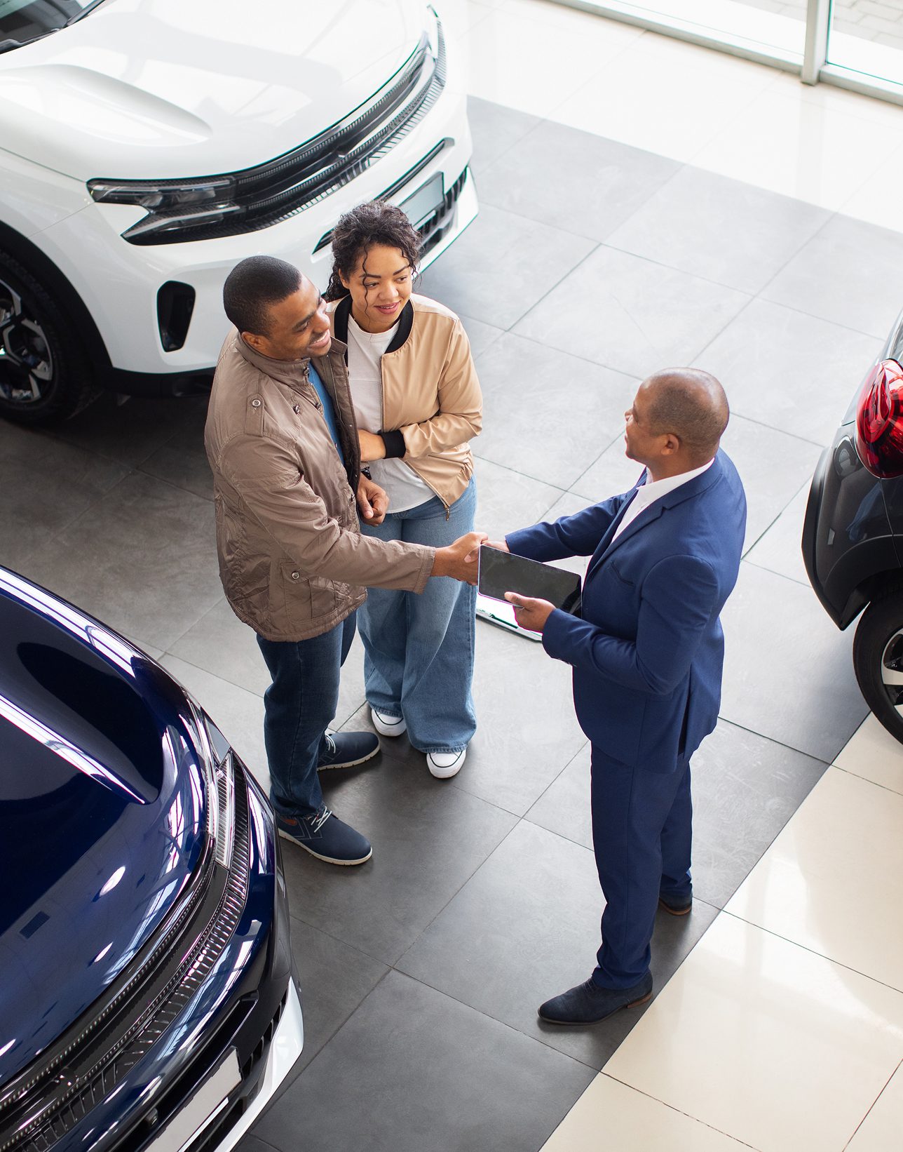 Salesman greeting couple in car showroom